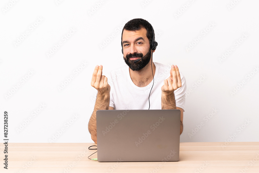 Telemarketer caucasian man working with a headset and with laptop making money gesture. Telemarketer caucasian man working with a headset and with laptop making money gesture.