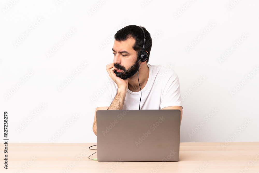 Telemarketer caucasian man working with a headset and with laptop having doubts. Telemarketer caucasian man working with a headset and with laptop having doubts.