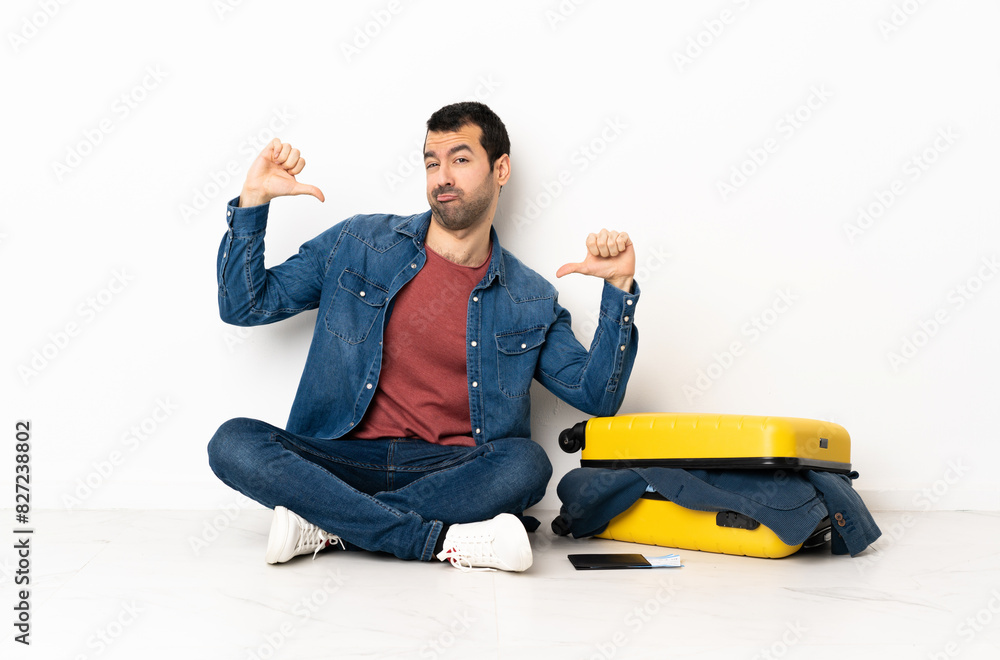 Caucasian handsome man with a suitcase full of clothes sitting on the floor at indoors proud and self-satisfied Caucasian handsome man with a suitcase full of clothes sitting on the floor at indoors proud and self-satisfied