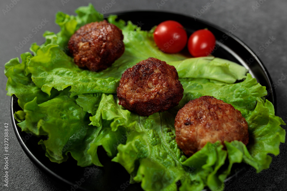 Fried cutlets on a lettuce leaf with tomato on a black background Fried cutlets on a lettuce leaf with tomato on a black background