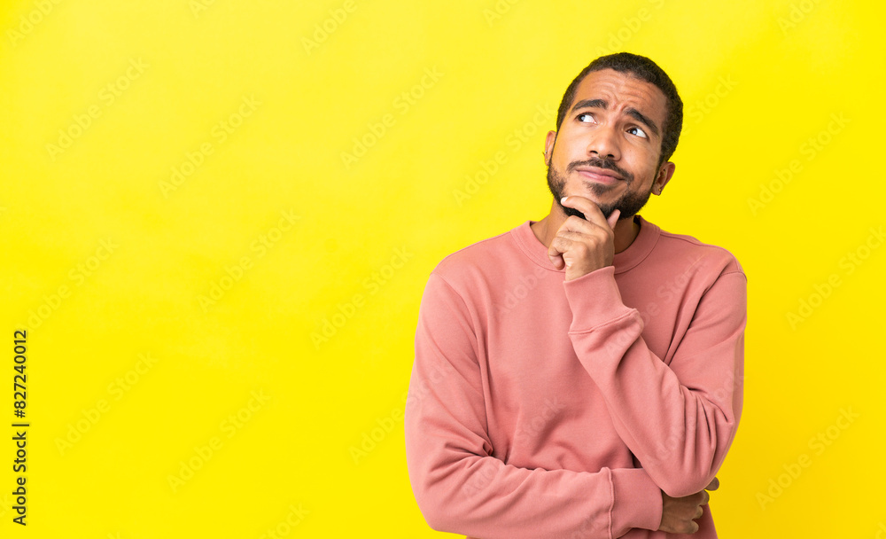 Young latin man isolated on yellow background and looking up Young latin man isolated on yellow background and looking up