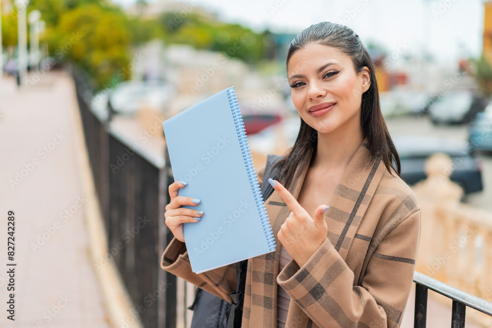 Young pretty student woman at outdoors and pointing it Young pretty student woman at outdoors and pointing it