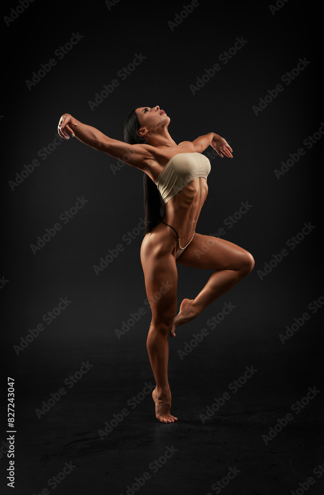 Sexy sports woman is dancing in a black studio. Sports underwear. Trained body.