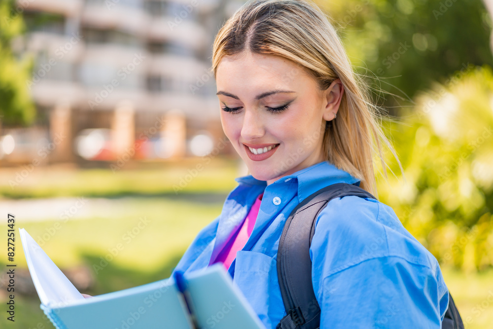 Young pretty blonde woman at outdoors holding a notebook Young pretty blonde woman at outdoors holding a notebook