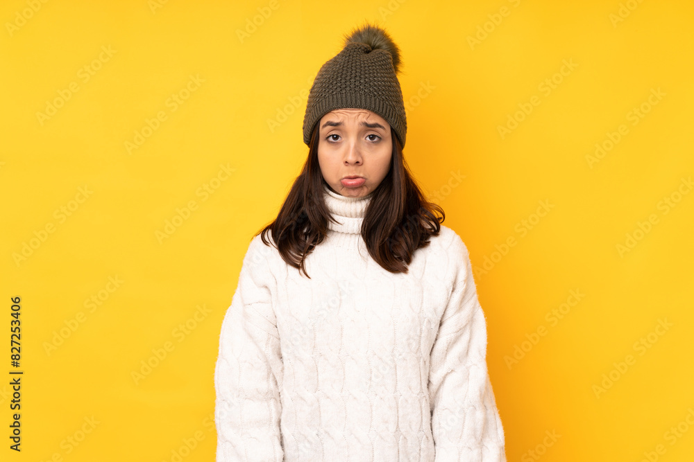 Young woman with winter hat over isolated yellow background with sad and depressed expression Young woman with winter hat over isolated yellow background with sad and depressed expression
