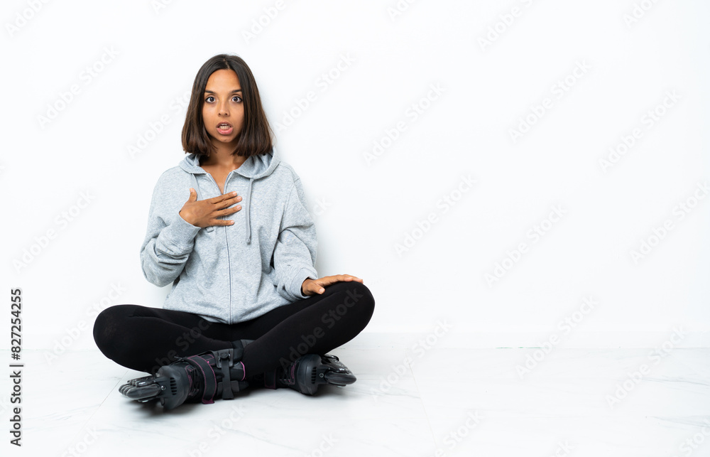 Young asian woman with roller skates on the floor surprised and shocked while looking right Young asian woman with roller skates on the floor surprised and shocked while looking right