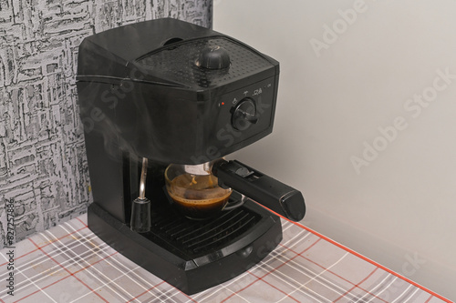 the coffee machine fills a glass cup with fragrant coffee photo