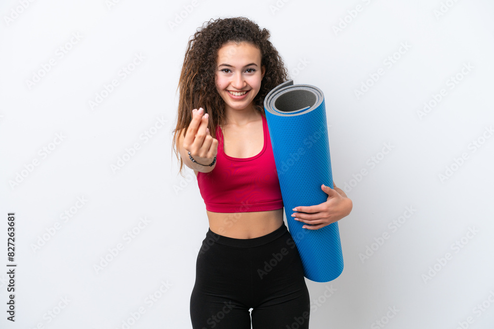 Young sport Arab woman going to yoga classes while holding a mat isolated on white background making money gesture Young sport Arab woman going to yoga classes while holding a mat isolated on white background making money gesture