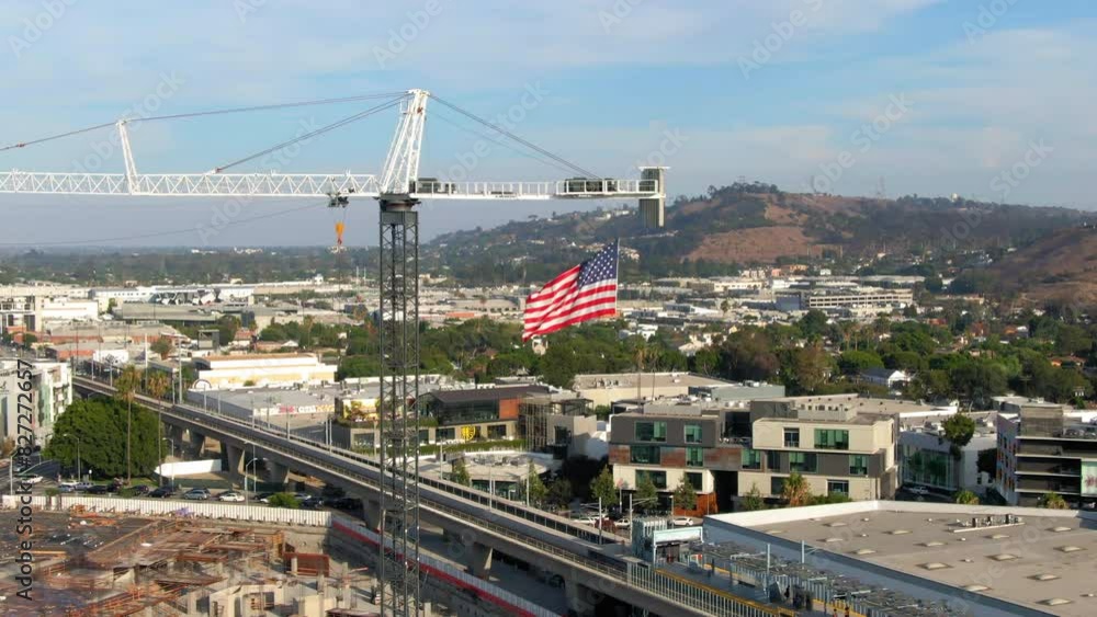 Aerial: Drone Panning Shot Of Flag Of United States Waving On Crane In Residential City With Hills During Sunny Day - Culver City, California Aerial: Drone Panning Shot Of Flag Of United States Waving On Crane In Residential City With Hills During Sunny Day - Culver City, California