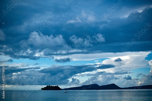 a boat on the water under a cloudy sky above islands