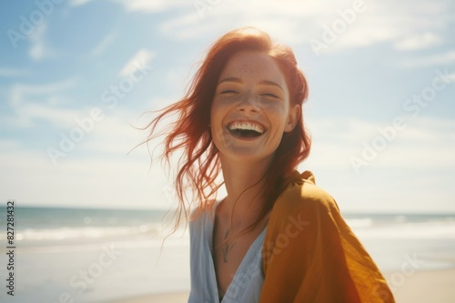 portrait of a redheaded woman, laughing happily on the beach