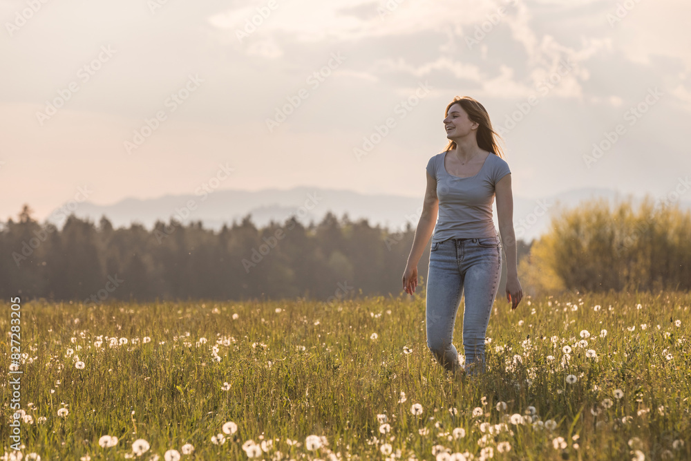 Young woman walking and relaxing on spring meadow at sunset Young woman walking and relaxing on spring meadow at sunset