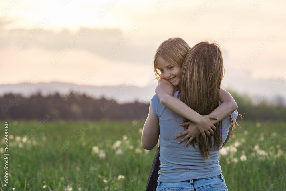 Little girl running to give her mother a gentle embrace, in the beautiful dandelion green field at sunset. Child love concept. Little girl running to give her mother a gentle embrace, in the beautiful dandelion green field at sunset. Child love concept.