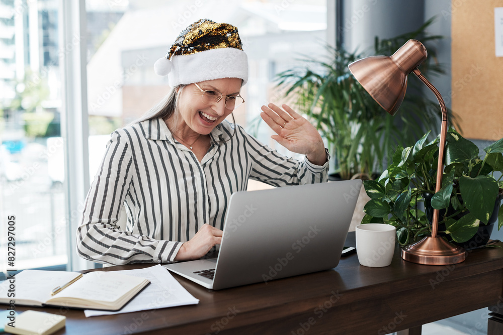 Video call, wave and mature woman in office with laptop for festive greeting, communication or networking. Christmas hat, brand manager and employee with hello for conference, online or meeting