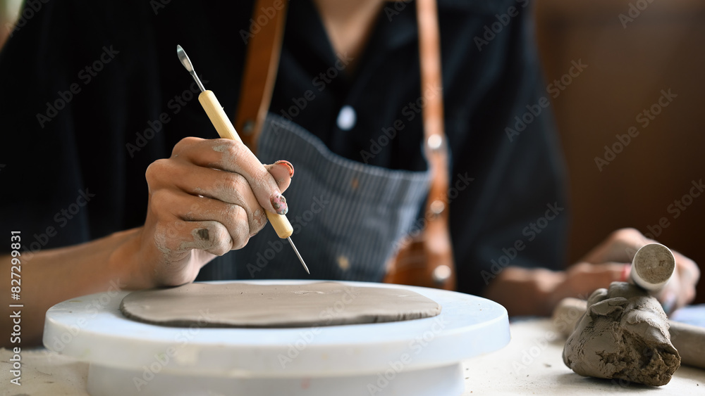 Close-up image of a Young artisan carving and decorating flatting clay with imprint
