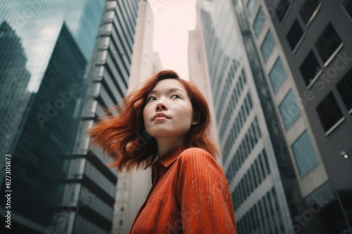 low angle portrait of confidence young woman standing against high rise city buildings in city