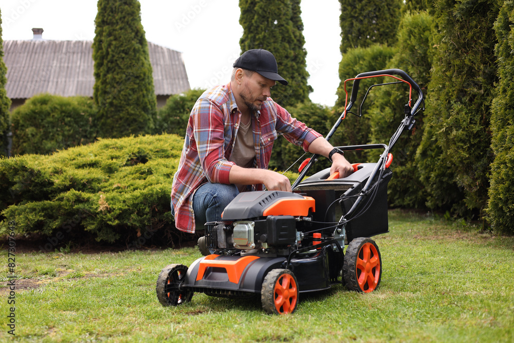Fototapeta premium Man with modern lawn mower in garden