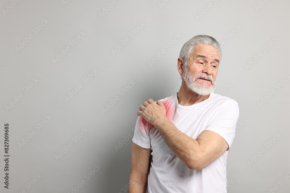 Senior man suffering from pain in shoulder on grey background. Space for text Senior man suffering from pain in shoulder on grey background. Space for text