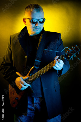 Portrait of a man with an electric guitar in his hands, made in a photo studio using color filters.