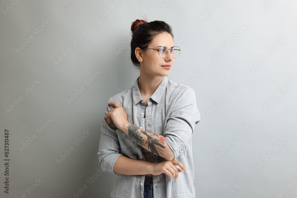 Fototapeta premium Portrait of beautiful tattooed woman on gray background