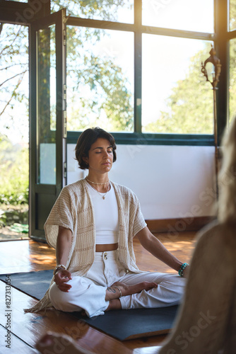 Free Download Young serene calm healthy Hispanic woman yoga coach meditating in studio doing breathing exercises for mind relaxation and mental balance at group yoga class or retreat training session. Vertical. - GFXLoad