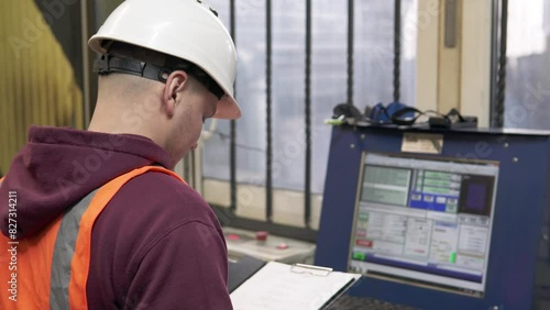 A CNC operator programs a plasma cutting machine in a workshop. An industrial worker enters commands into a computer program to produce metal parts.	 photo