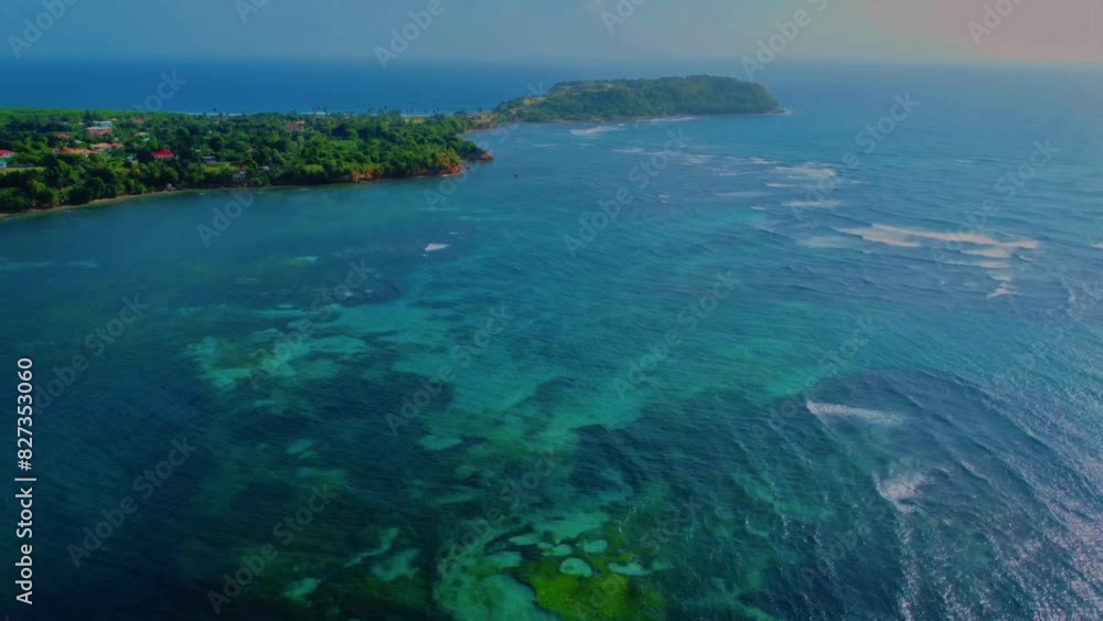 Drone scenery of a green island with serene blue ocean on a sunny day Drone scenery of a green island with serene blue ocean on a sunny day