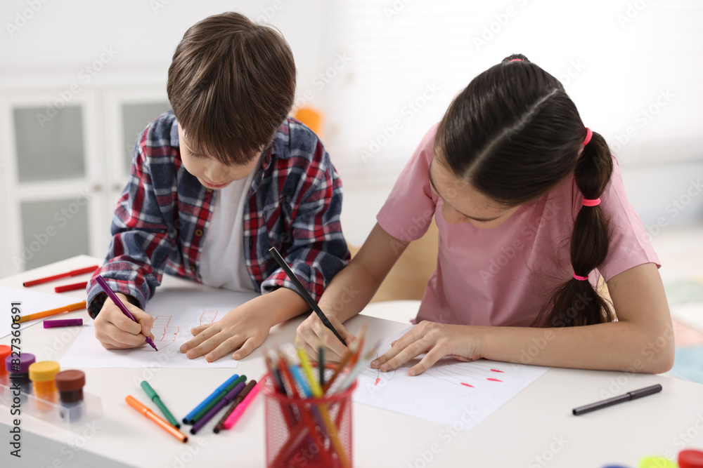 Happy brother and sister drawing at white table in room Happy brother and sister drawing at white table in room