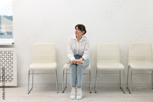 Woman sitting on chair and waiting for job interview indoors