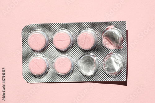 The tablets are in silver packaging on a pink background.