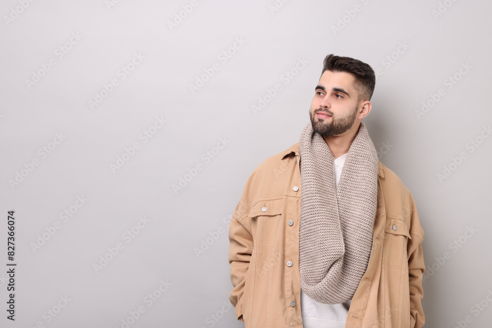Fototapeta premium Handsome man in warm scarf on light grey background. Space for text