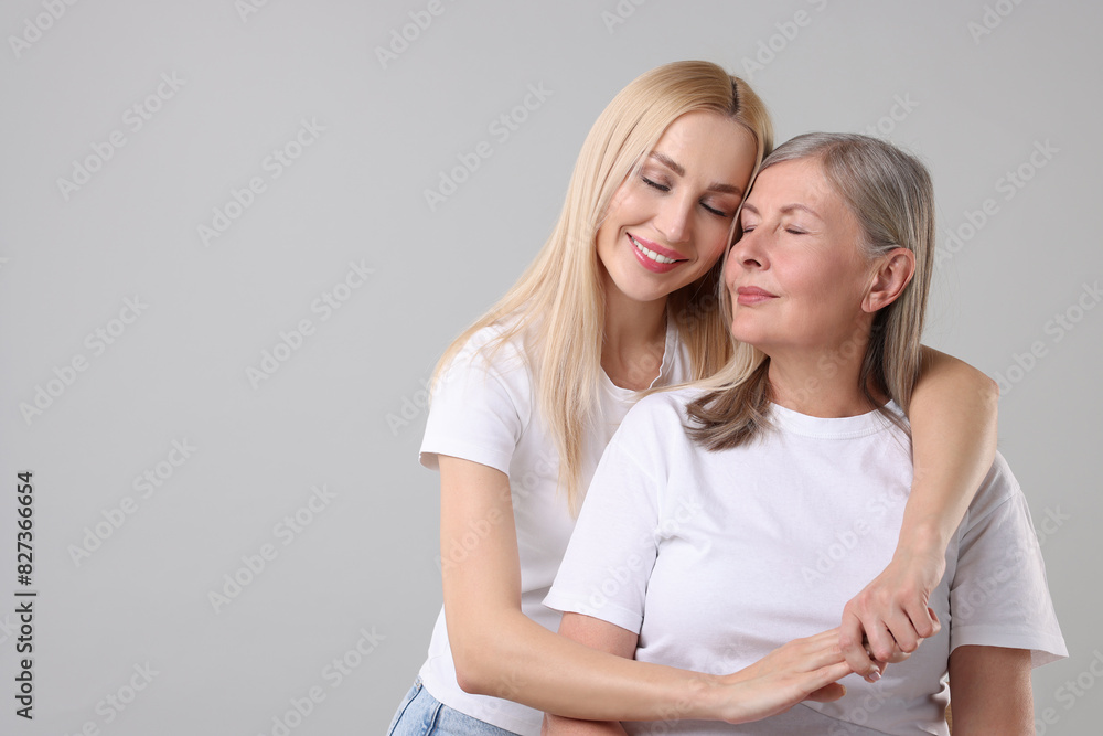 Family portrait of young woman and her mother on light grey background. Space for text Family portrait of young woman and her mother on light grey background. Space for text