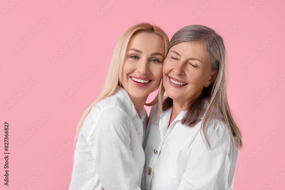 Family portrait of young woman and her mother on pink background Family portrait of young woman and her mother on pink background