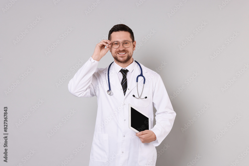 Portrait of smiling doctor with tablet on light grey background Portrait of smiling doctor with tablet on light grey background