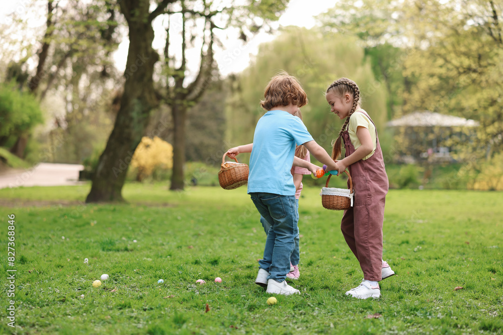 Easter celebration. Cute little children hunting eggs outdoors, space for text Easter celebration. Cute little children hunting eggs outdoors, space for text