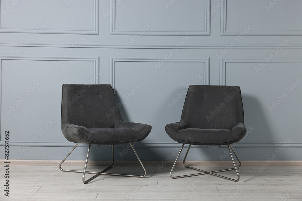 Fototapeta premium Comfortable armchairs near grey wall in room