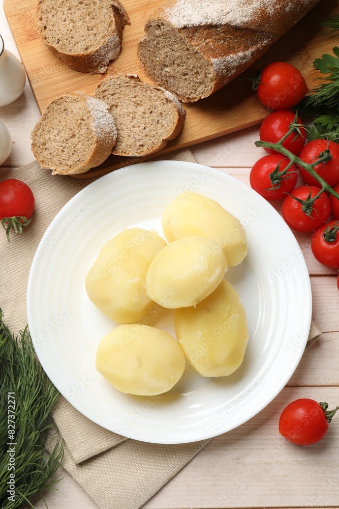 Plate with young boiled potatoes and products on light wooden table, flat lay Plate with young boiled potatoes and products on light wooden table, flat lay