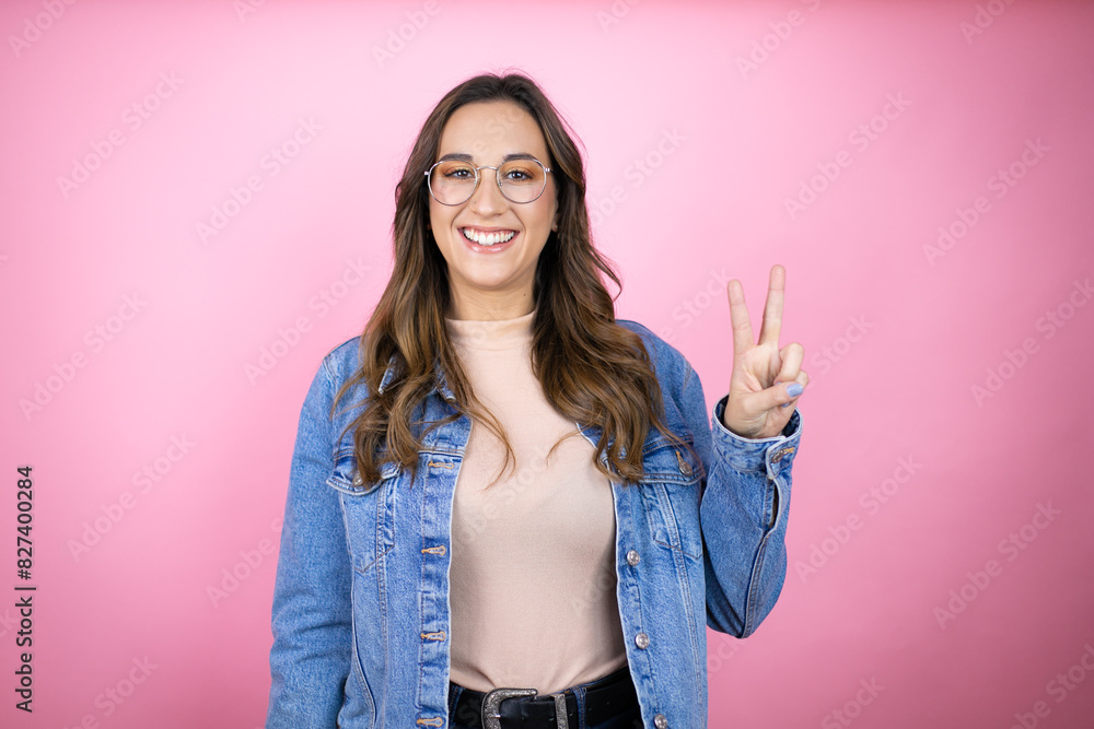 Young beautiful woman wearing denim jacket over isolated pink background showing and pointing up with fingers number two while smiling confident and happy Young beautiful woman wearing denim jacket over isolated pink background showing and pointing up with fingers number two while smiling confident and happy