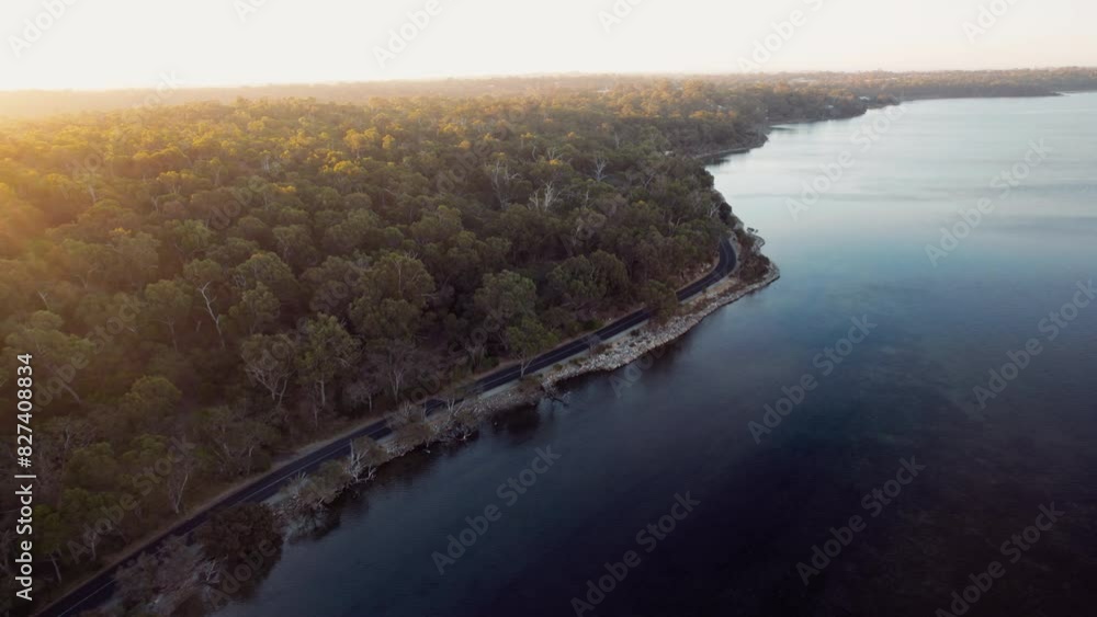 An aerial perspective captures a tranquil forest bordering a calm lake during sunset in the autumn season, exuding peace and natural beauty. An aerial perspective captures a tranquil forest bordering a calm lake during sunset in the autumn season, exuding peace and natural beauty.