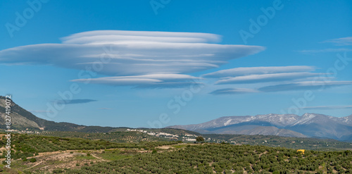 Huge lenticular clouds over the snowy peaks of the Sierra Nevada in Granada (Spain) at sunset