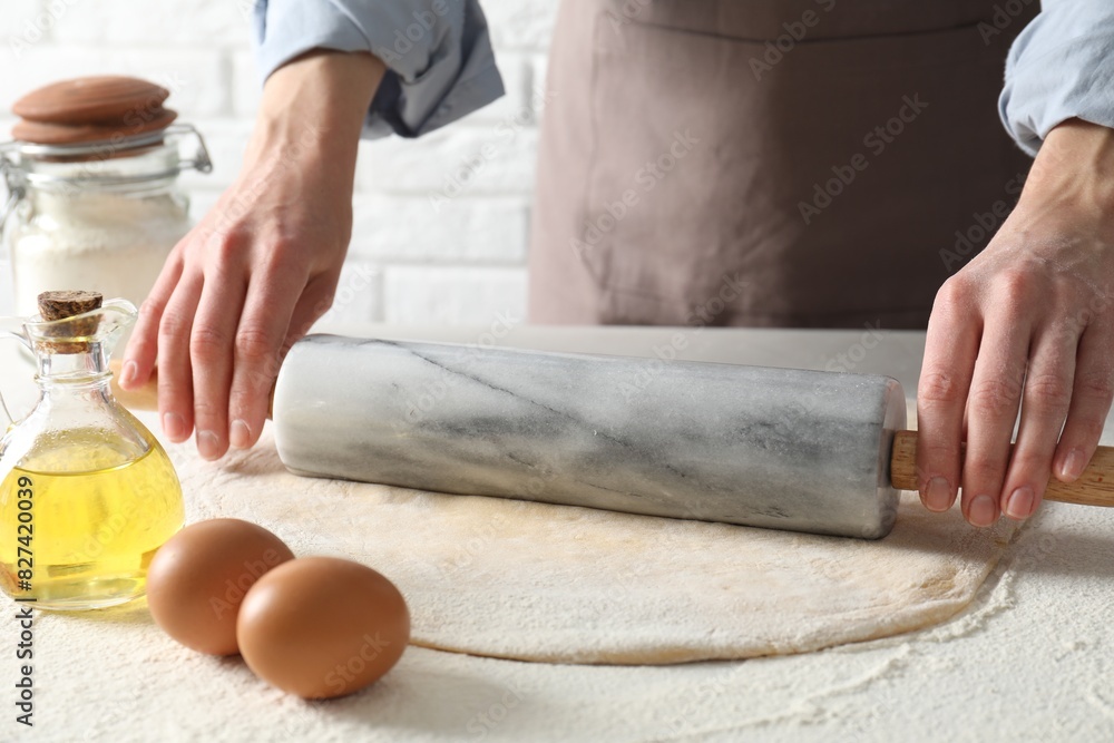 Fototapeta premium Woman rolling raw dough at table, closeup