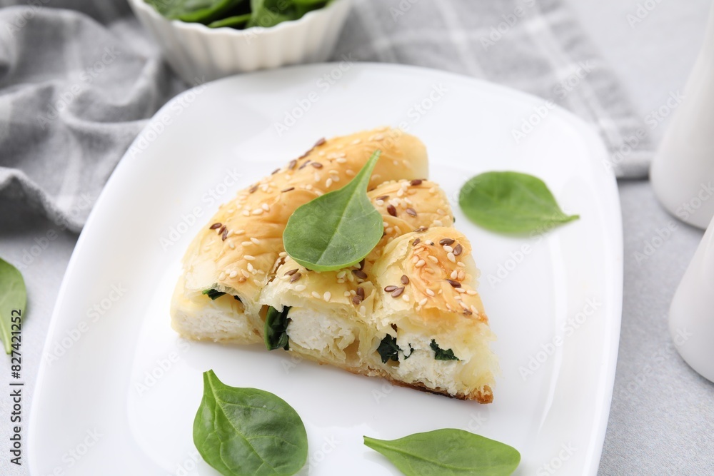 Piece of delicious puff pastry with spinach on light table, closeup Piece of delicious puff pastry with spinach on light table, closeup