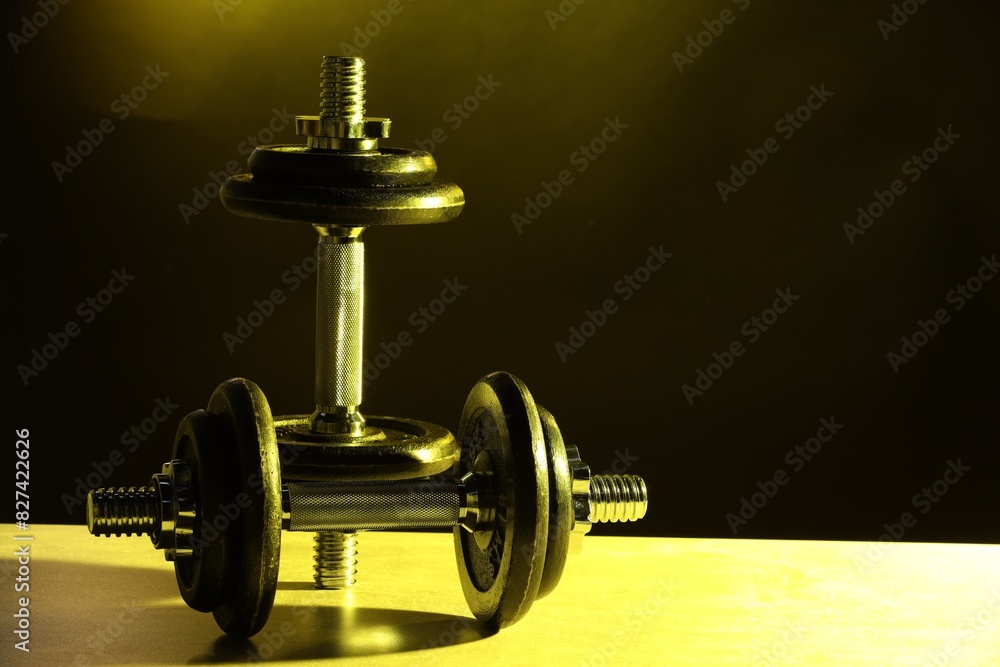 Two barbells on table in color lights. Space for text Two barbells on table in color lights. Space for text