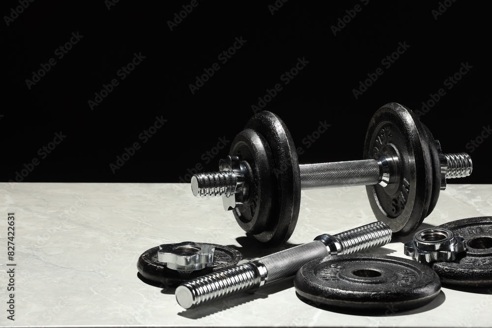 Barbell and parts of one on light table against black background. Space for text Barbell and parts of one on light table against black background. Space for text