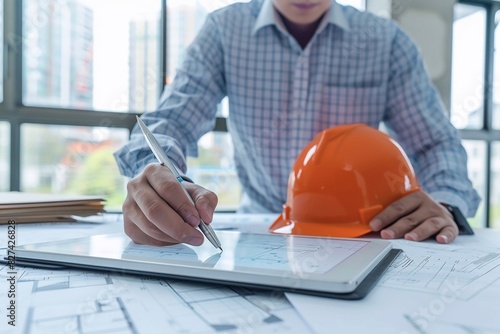 Businessman using a digital pen to annotate construction plans on a tablet, representing innovation photo