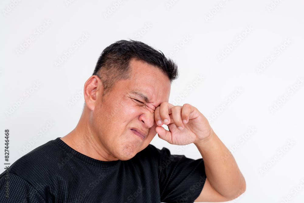 Image of a middle aged Asian man expressing discomfort while rubbing his irritated eyes, isolated on a white background. Image of a middle aged Asian man expressing discomfort while rubbing his irritated eyes, isolated on a white background.