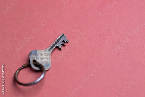 A metal key on a pink background with space fro text