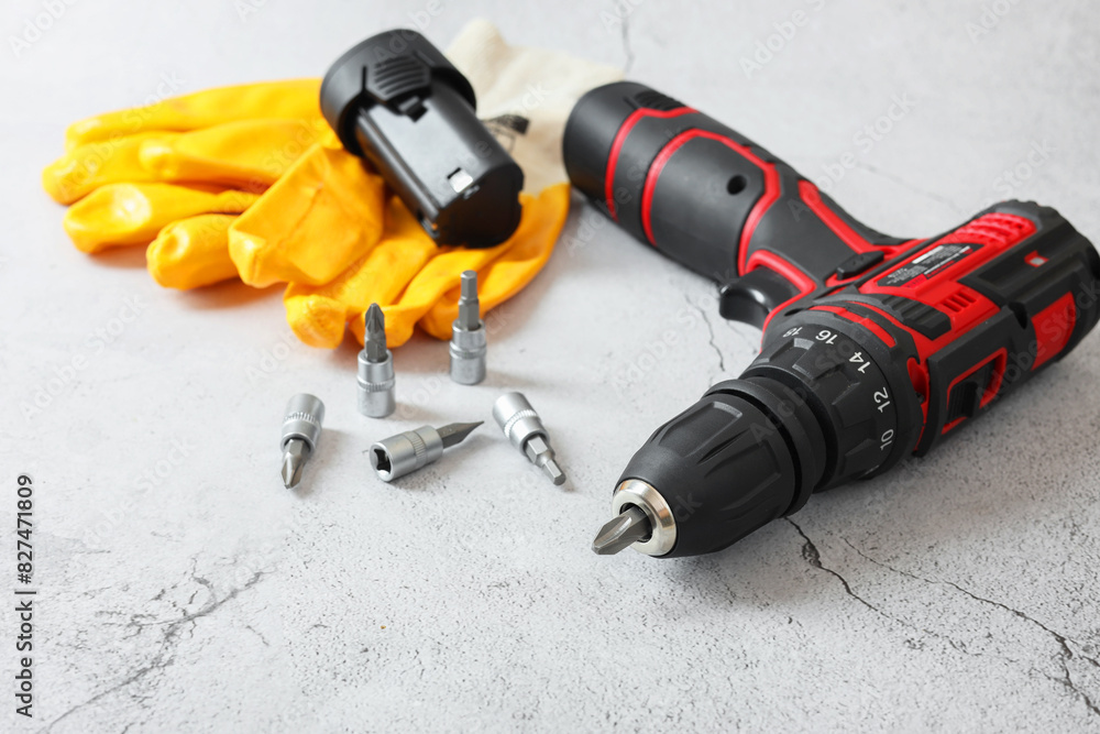 Electric screwdriver, drill bits, battery and gloves on light table Electric screwdriver, drill bits, battery and gloves on light table