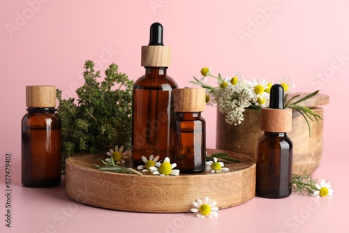 Aromatherapy. Different essential oils and flowers on pink background