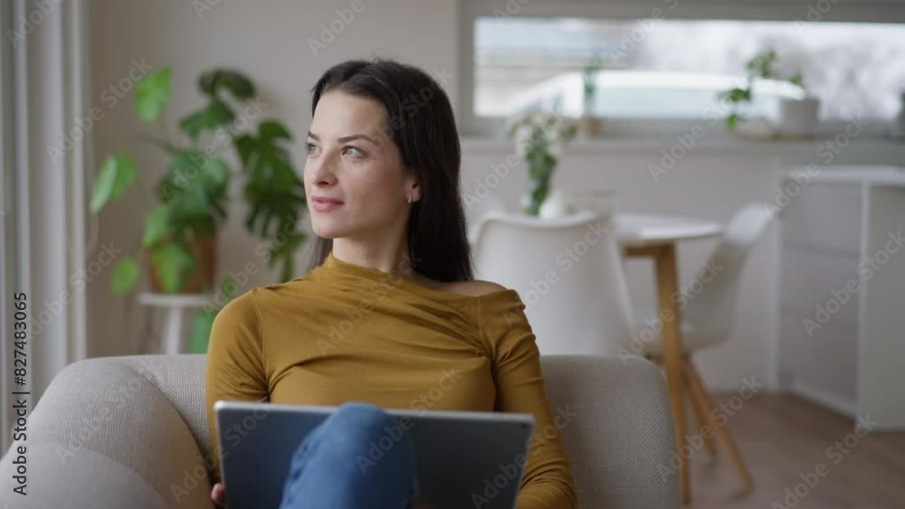 Woman sitting on sofa, managing household functions of smart home system. Woman shopping online, paying online or e-learning on tablet. Woman sitting on sofa, managing household functions of smart home system. Woman shopping online, paying online or e-learning on tablet.
